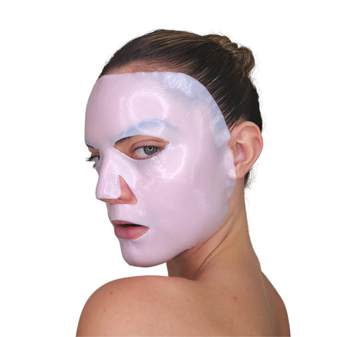 A person with light skin and brown hair in a bun wears the Velez Intense Hydration Cellulose Face Mask, known for promoting skin regeneration, while looking over their shoulder neutrally against a plain white background.