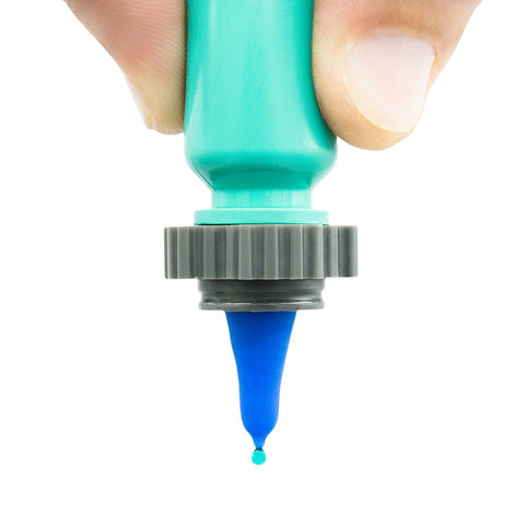 A hand holds a turquoise Nanodropper Eye Drop Extender Adaptor with a gray nozzle, as a bright blue droplet forms at the tip. The white background accentuates Nanodroppers innovative design that reduces drops by 60%, minimizes waste, and simplifies application.