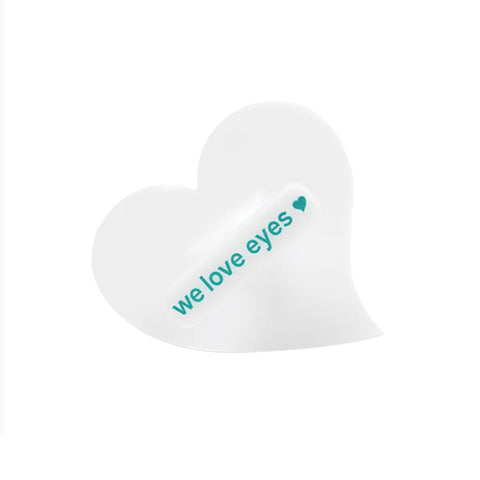 The heart-shaped white patch with we love eyes in teal and a small teal heart represents eyelid hygiene. This design complements the We Love Eyes Mini Eyelid Scrub Mitt, offering gentle and effective antimicrobial cleansing.