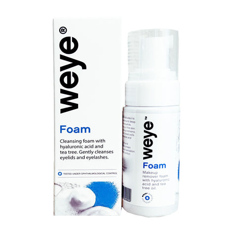 A white bottle of Weye Foam sits beside its packaging. The box and bottle, adorned with black text, describe this cleanser: a 60mL gentle formula with hyaluronic acid, tea tree, chamomile, and calendula for eyelid hygiene and effective cleaning of lashes to help prevent blepharitis.