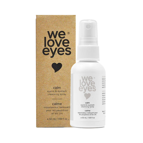 A We Love Eyes Calm Eyelid & Eyelash Cleansing Spray with HypoChlorous, housed in a white bottle featuring black text and a heart icon, sits beside its brown cardboard box. A soothing chamomile infusion and convenient spray nozzle complete its minimalist design.