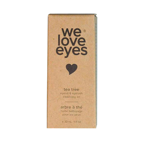 A cardboard box displays We Love Eyes with a heart icon, labeled in English and French as Tea Tree & Jojoba Oil Eyelid & Eyelash Cleansing Oil. The box is 30 ml / 1 fl oz, promoting healthy meibomian oil glands.