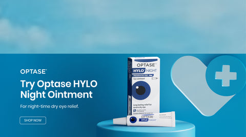 Packaging of Optase HYLO Night Ointment is displayed on a blue pedestal. Text reads: Optase. Try Optase HYLO Night Ointment. For night-time dry eye relief. A heart symbol with a medical cross is in the background. Shop Now button is visible.