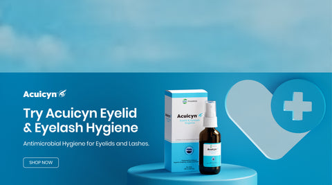 A spray bottle and its packaging are displayed against a blue background. Text reads Try Acuicyn Eyelid & Eyelash Hygiene and Antimicrobial Hygiene for Eyelids and Lashes. A heart with a medical cross is in the background.
