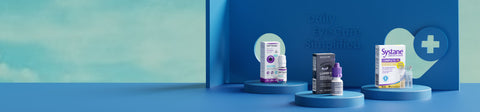 Display of eye care products on blue platforms against a soft blue background. Two boxes with a small bottle between them and one bottle placed centrally. A cross symbol and text Daily Eye Care Simplified are visible in the background.