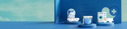 A display of eye care products on a blue podium against a teal background. The setup includes eye wipes and solution packs with a medical cross symbol. Text reads, Daily Eye Care Simplified.