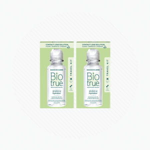 Two boxes of Bausch + Lomb BioTrue Multipurpose Contact Lens Solution Travel Kit (2x 2oz 60mL) rest on a white, striped background. Each box contains a clear bottle with the brand and product name, ideal for maintaining silicone hydrogel lenses while traveling.