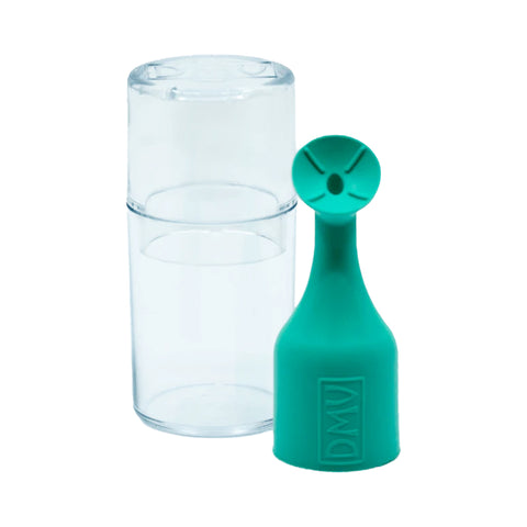 A small, transparent cylindrical container is next to a teal, bottle-like object resembling an illuminated inserter. Its circular top has a cross-shaped cutout with engraved letters, indicating its part of the DMV Luma-Serter Contact Lens Insertion and Removal Tool (5-Pack Green).