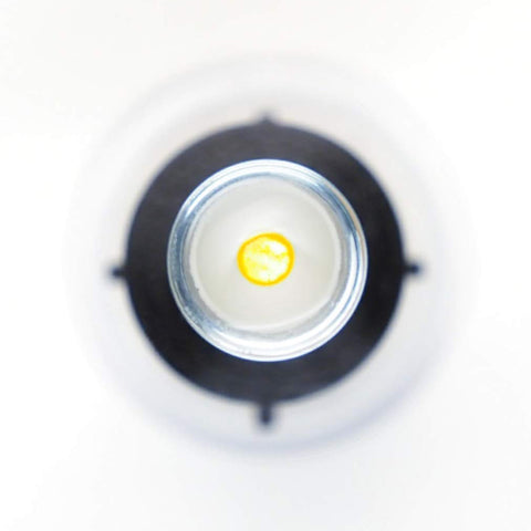 An overhead shot captures the S5 Mini Inserter by Augmented Vision Labs, resembling a small, round container with a yellow interior. It sits centrally on a larger circular black and white backdrop, giving the image an abstract feel with soft focus. Free video training is included.