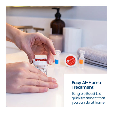 Hands opening a container on a bathroom countertop with bottles and towels nearby. Text reads, Easy At-Home Treatment. Tangible Boost 2-Pack, designed to restore and maintain your Tangible Hydra-PEG coated lenses, offers a quick at-home treatment.