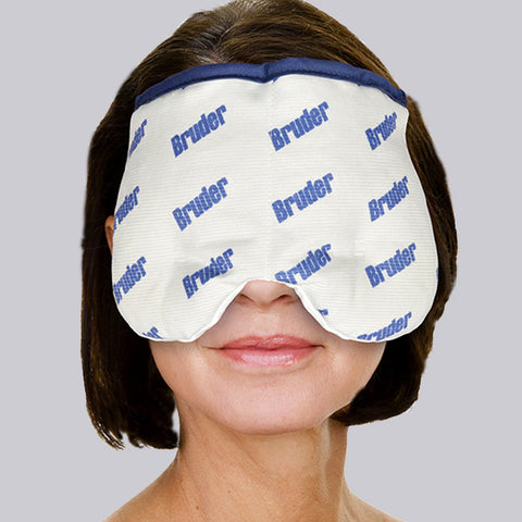 A woman uses the Bruder Moist Heat Sinus Compress over her eyes and nose, set against a plain gray background. The white compress, featuring blue text, is designed with a curved shape for a snug facial fit.