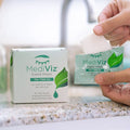 Hands open a sachet from the PRN - Physician Recommended Nutriceuticals MediViz Tea Tree Eyelid Wipes 3-Pack, featuring a green leaf design. The wipes offer relief for dry, irritated eyes and ensure cleaner, healthier eyelids, perfectly displayed on a countertop.