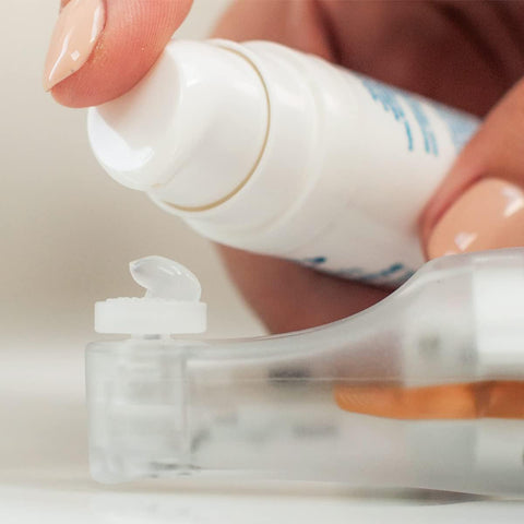 A close-up shows a finger pressing the pump of the NuLids device, dispensing clear gel onto a surface. The background is blurred, highlighting the hand and NuSight Medicals innovative NuLids All Natural At-home Dry Eye Treatment 180 for eyelid hygiene.