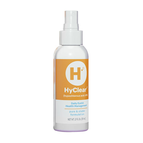 A white spray bottle with an orange label reads Contamac and contains Hyclear Hypochlorous Spray, featuring 0.01% hypochlorous acid for daily eyelid hygiene. Its pure and stable formulation ensures optimal eyelid health management, offering a 1-2 month supply in its 60 ml (2 fl oz) container.