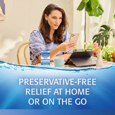 A woman sits at a table using her phone and tablet with coffee, a plant, and flowers nearby. Beside her are Refresh Optive Lubricant Preservative-Free Eye Drops by Abbvie, promising preservative-free dry eye relief at home or on the go.
