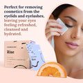 A woman gently cleans her closed eye with a CorneaCare Wipe infused with tea tree oil. A box and sachet of CorneaCare Wipes (30ct) are displayed, stating: Perfect for removing cosmetics from the eyelids and eyelashes. An orange slice is shown at the bottom.