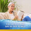 An elderly person with long gray hair reads on a couch, surrounded by green plants. The image recommends Abbvies Refresh Optive Mega-3® Preservative-Free Lubricant Eye Drops (60 vials) for lipid-enhanced relief from dry eyes due to MGD.