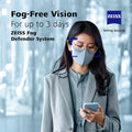 A person with glasses and a face mask looks at their smartphone. Text promotes the ZEISS Fog Defender System Anti-Fog Spray for Glasses, which offers Fog-Free Vision for up to 3 days. The blurred indoor background highlights clarity within the haze.
