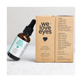 A small amber bottle labeled We Love Eyes - 100% All Natural Tea Tree Makeup Remover Oil with a dropper lid leans against two cardboard boxes. It contains Australian Tea Tree Oil and is vegan, cruelty-free, as well as free from sulfates, gluten, and parabens.